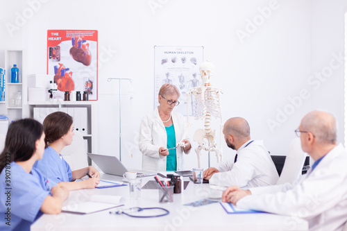 Medical scientins demonstrating on human skeleton model for team of physicians. Clinic expert therapist talking with colleagues about disease, medicine professional