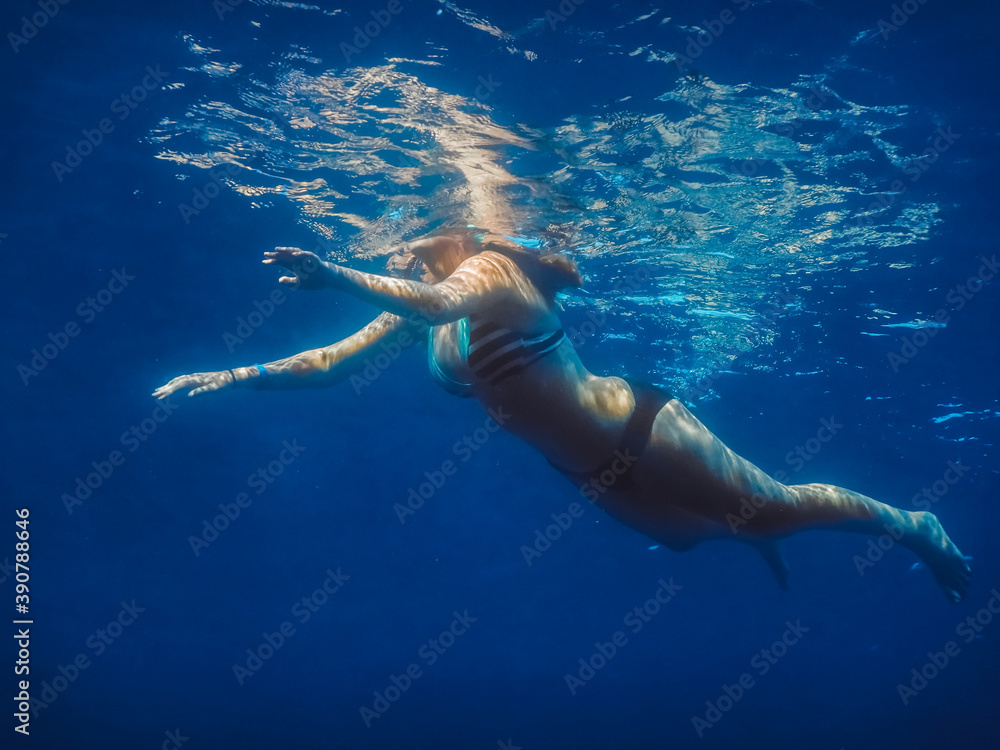 woman in bikini swims on the surface in the sea on vacation