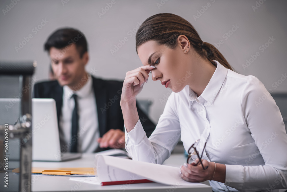 Woman in profile studying document sitting in office Woman in profile studying document sitting in office