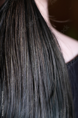 Women's hairstyle tail. back view on black t-shirt background close-up. Copy-space.