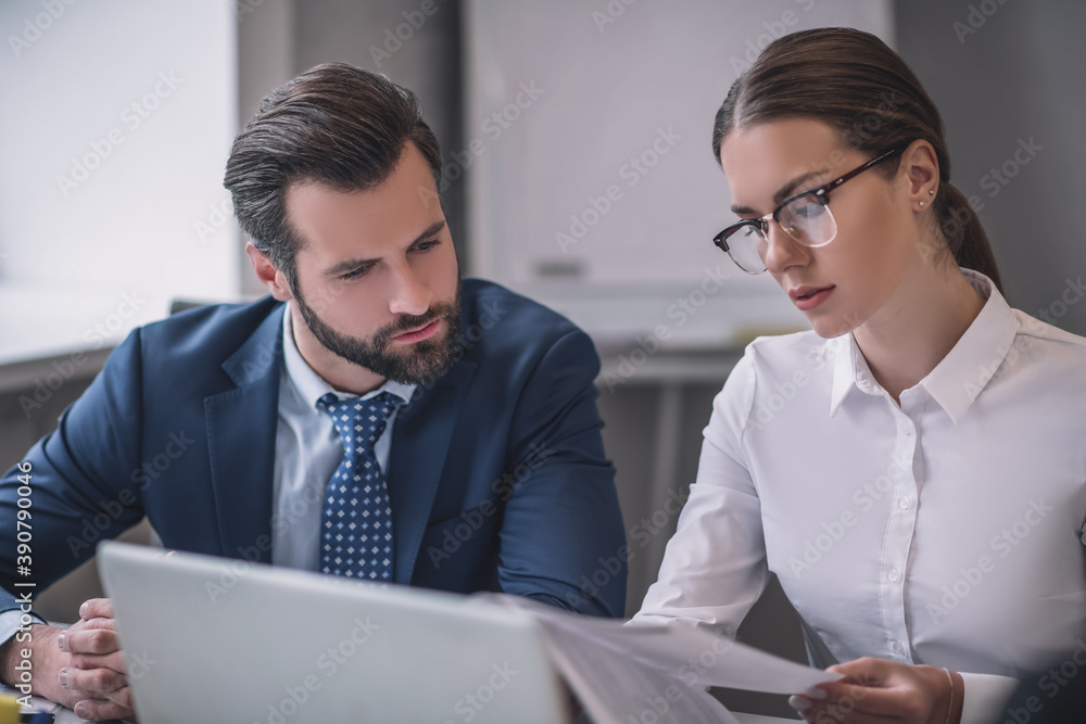 Bearded man and woman in glasses looking at documents Bearded man and woman in glasses looking at documents