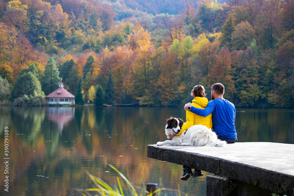 Couple in love with dog relaxing at the lake.