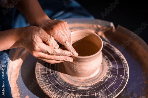 Women hands. Potter at work. Creating dishes. Potter's wheel. Dirty hands in the clay and the potter's wheel with the product. Creation. Working potter.