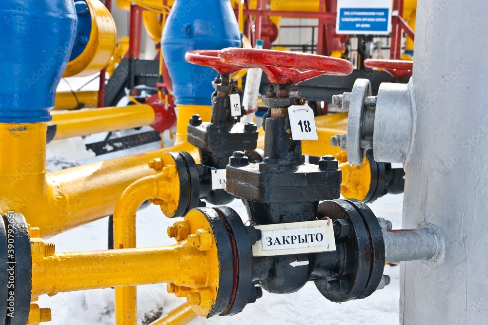 Red valves and a system of colorful pipes with signs 