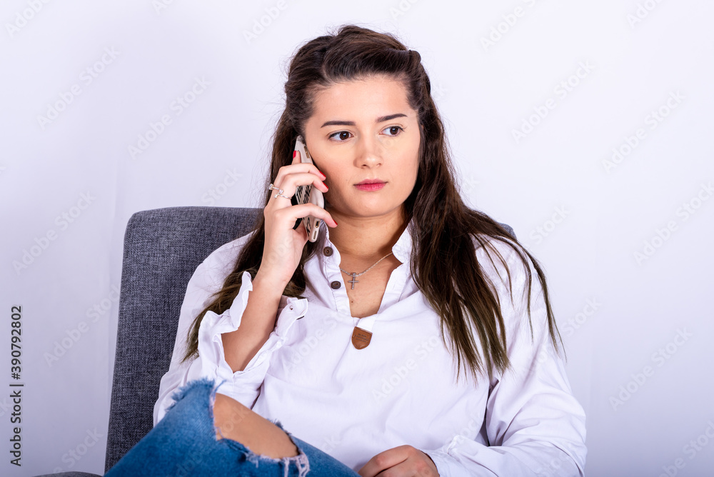a young girl is sitting in an armchair and using a mobile phone a young girl is sitting in an armchair and using a mobile phone