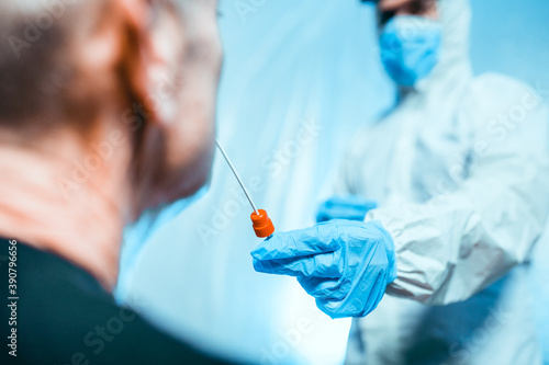 Fotografi Medico con tuta covid fa il test del tampone molecolare per coronavirus nasale a