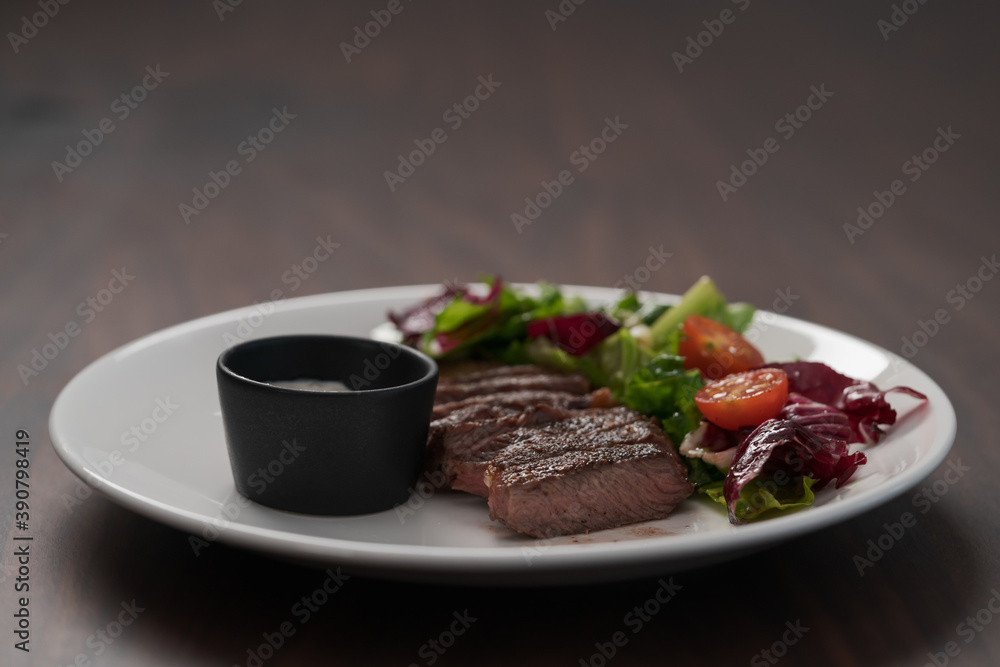 ribeye steak with garlic sauce and fresh salad on white plate on walnut table ribeye steak with garlic sauce and fresh salad on white plate on walnut table