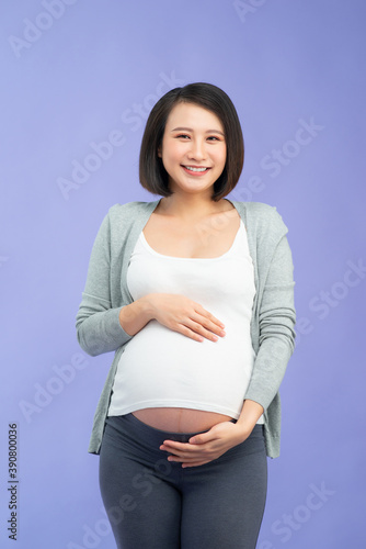 Happy pregnant woman posing on color background