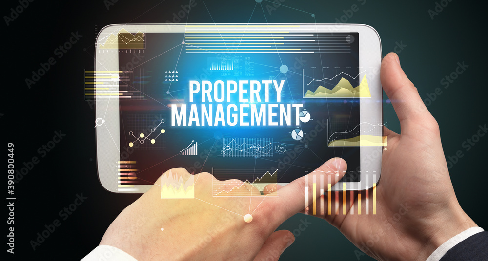 Close-up of hands holding tablet with PROPERTY MANAGEMENT inscription, modern business concept Close-up of hands holding tablet with PROPERTY MANAGEMENT inscription, modern business concept