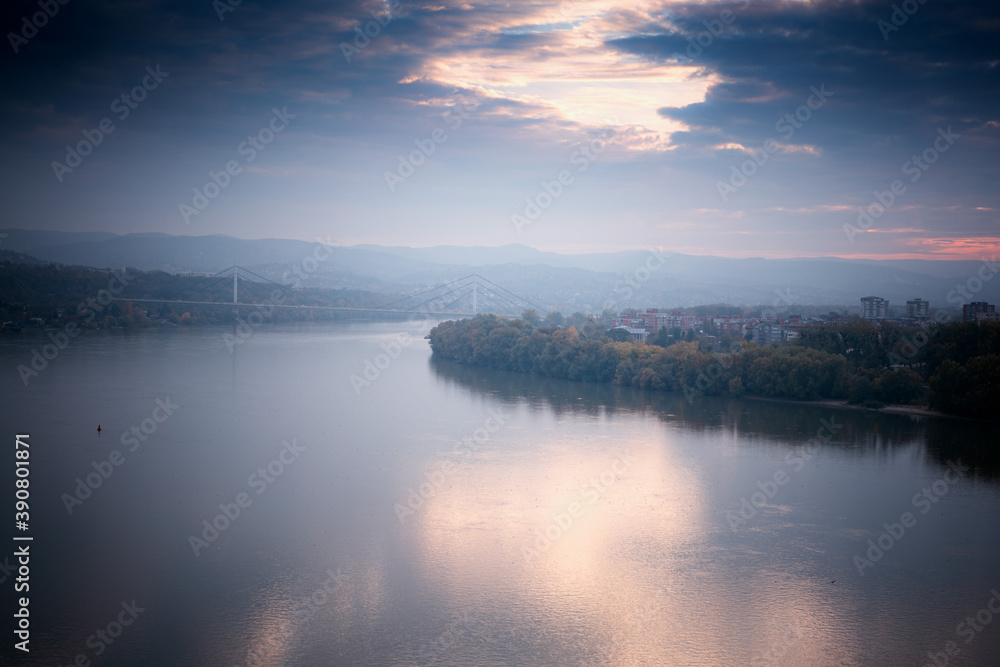 Beautiful autumn landscape, Danube river on a foggy cloudy day, clouds and sky are reflected in water