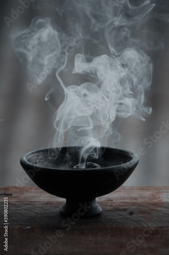 Vertical shot of a burning incense in a black bowl photo