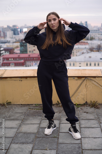 Full height photo of young woman, standing on roof of tall building in large city. © rodionkarimov