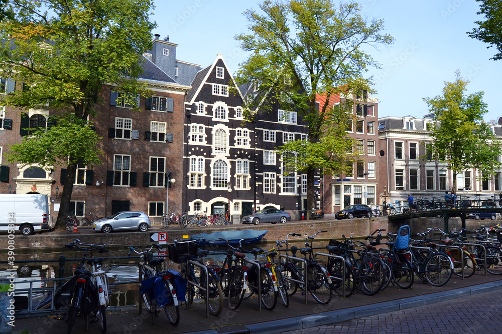 Traditional dutch architecture, facades of houses in Amsterdam, canal and bicycle parking. The Netherlands in summer time.
