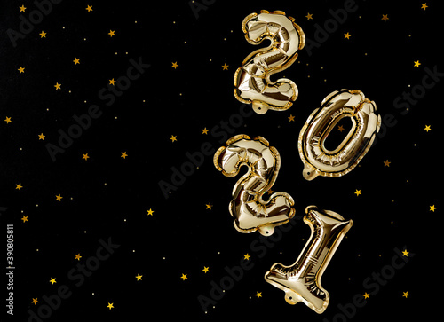 Happy New year 2021 celebration. Gold foil balloons numeral 2021 and gold confetti on black background. New year concept. Flat lay