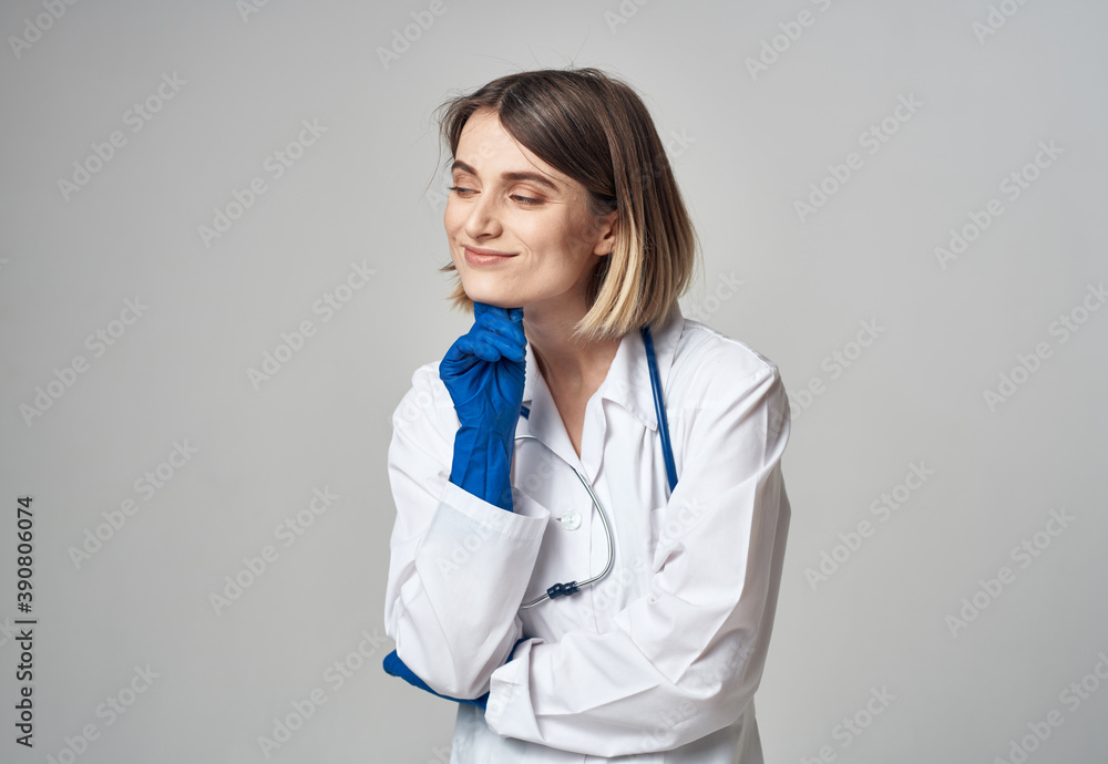 portrait of a nurse in gloves and a medical gown on a light background portrait of a nurse in gloves and a medical gown on a light background