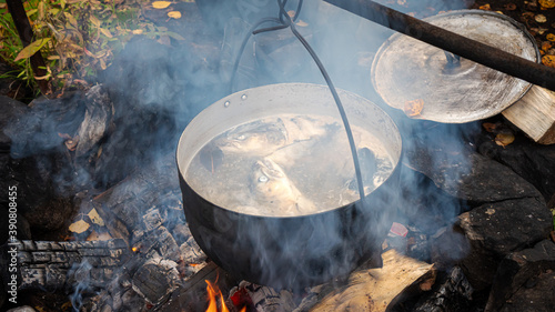 Cooking fish soup over an open fire in a kettle. Camping kitchen.