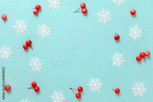Christmas sale. Red berry, white snowflakes in shape frame on pastel blue background for greeting card. Xmas backdrop with space for text.