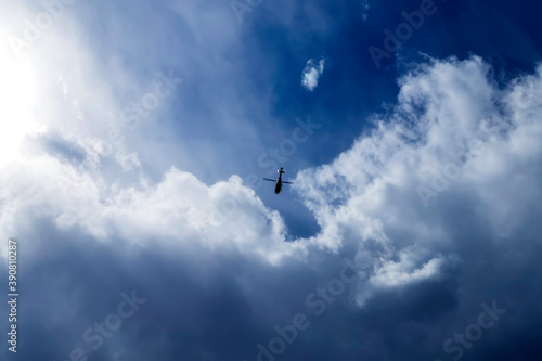 Blue sky with small helicopter flying into a thundercloud. © sergofan2015