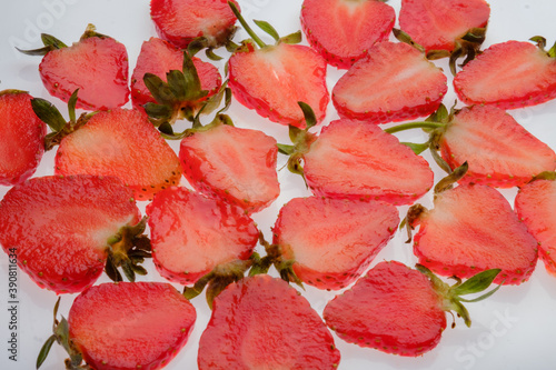 ripe Strawberry slices with green fresh leaves on a white background close up