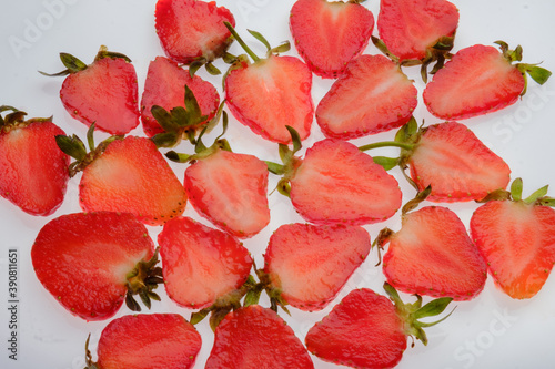 ripe Strawberry slices with green fresh leaves on a white background close up