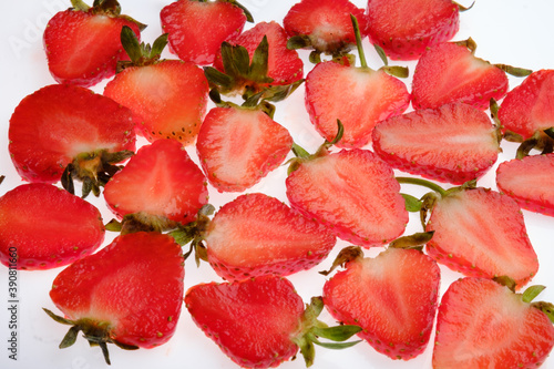 ripe Strawberry slices with green fresh leaves on a white background close up