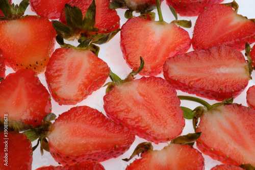 ripe Strawberry slices with green fresh leaves on a white background close up