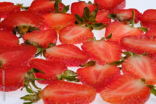 ripe Strawberry slices with green fresh leaves on a white background close up