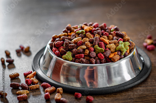 Dry Colorful cat food in metal bowl on wooden background photo