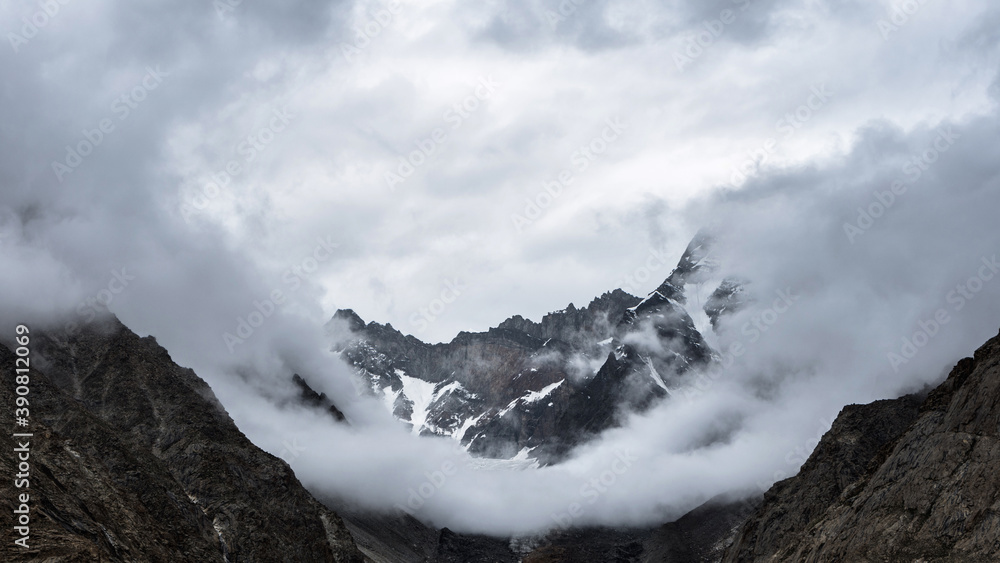 View of a mountain ridge surrounded by clouds on an overcast day in Karakoram, Pakistan