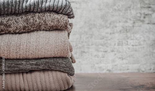 Stack of cozy knitted sweaters on gray wall background