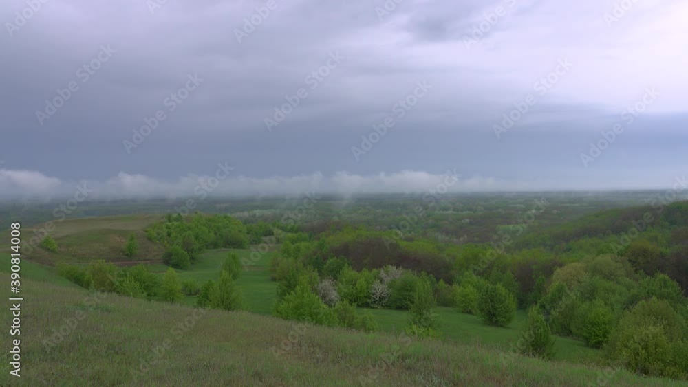 White clouds on the background of rain clouds on the background of the forest in the haze and the river, rural landscape. White clouds on the background of rain clouds on the background of the forest in the haze and the river, rural landscape.