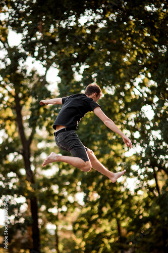 view of man jumping up in the air against the backdrop of green trees