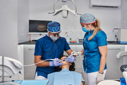 Professional dentists examine woman s teeth in the dental office.