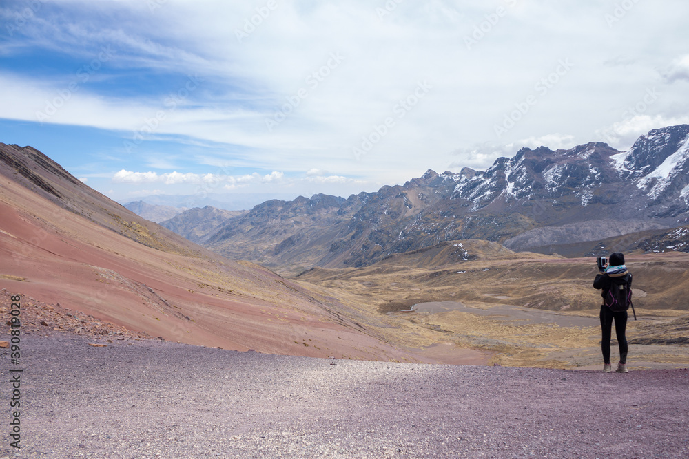 A woman enjoying the view of the red mountains near the rainbow mountain ( winicunca ) near the city of cusco - Peru