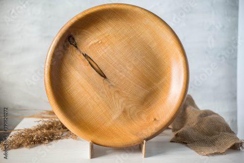 Handmade wooden plate on a stand. Craft textured tableware. Wood texture