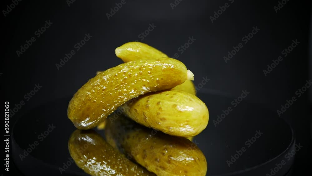 Three Pickled Gherkins Spinning Over Black Background - Fermented Cucumbers. - close up Three Pickled Gherkins Spinning Over Black Background - Fermented Cucumbers. - close up
