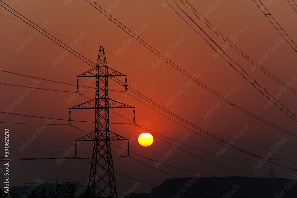 Fototapeta premium Sunset behind high voltage power towers