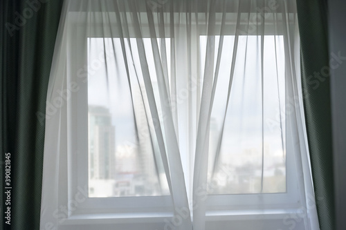 fabric transparent white thin curtain on large window blowing by light wind