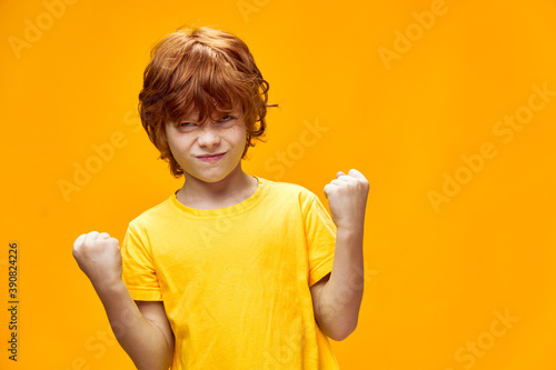 red-haired boy holding hands in fists on isolated background