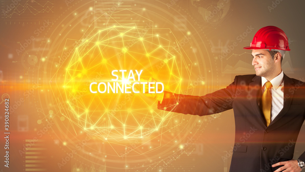 Handsome businessman with helmet drawing STAY CONNECTED inscription, social construction concept Handsome businessman with helmet drawing STAY CONNECTED inscription, social construction concept