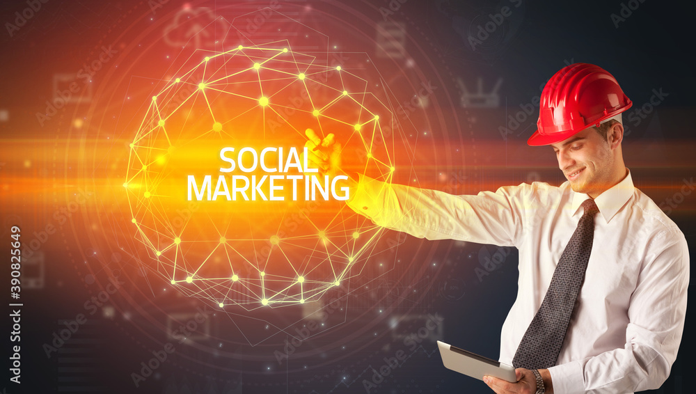 Handsome businessman with helmet drawing SOCIAL MARKETING inscription, social construction concept Handsome businessman with helmet drawing SOCIAL MARKETING inscription, social construction concept