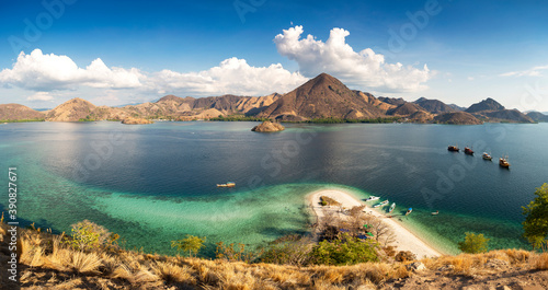 Panormaric view of Komodo islands, Indonesia, from top of hill with mountains in background and crystal clear sea in foreground