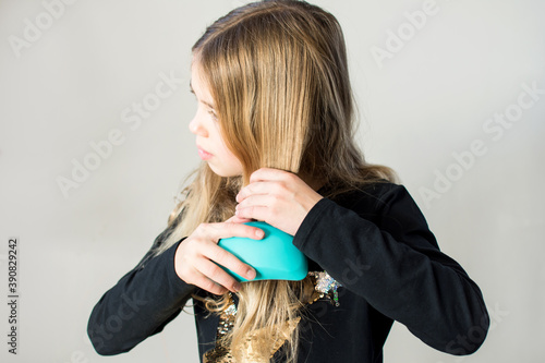 Young brunertte girl is combing tangled her hair at home.  photo