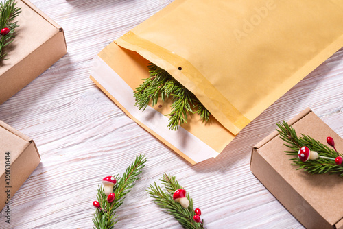Brown bubble envelope abd cardboard boxes decorated with christmas tree ornament on wooden background