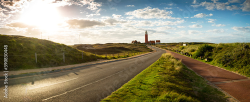 Road to iconic lighthouse surrounded by houses during sunset at the island of Texel, The Netherlands photo