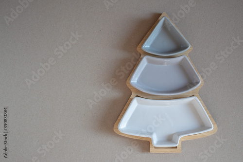 The dish is in the form of a Christmas tree, divided into portions. Three small empty serving dishes on a wooden stand in the shape of a Christmas tree. Dishes for the new year's table. New year's ser