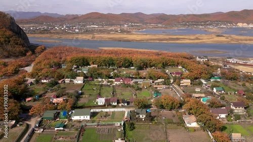 Aerial view: The camera flies over the sea village of Smychka in the Primorsky Territory. A beautiful lake surrounded by hills and a Russian village photo