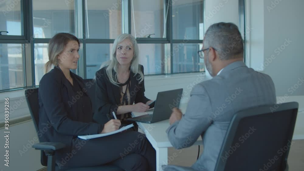 Serious female employer and HR manager interviewing mature male professional at meeting table. Static shot. Business meeting or job interview concept Serious female employer and HR manager interviewing mature male professional at meeting table. Static shot. Business meeting or job interview concept
