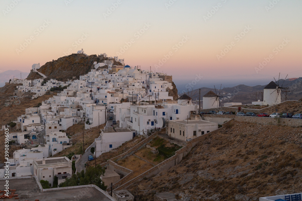Fototapeta premium Serifos village, Serifos island, Greece. A view of the village after the sunset. Blue hour. White houses with Cycladic architecture, on the hill. The sea and the sky in deep blue and orange colors.