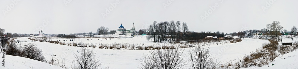 The panoramic view of Suzdal in winter on the Kamenka river, Cathedral of the Nativity of the Theotokos and the Kremlin in Russia.